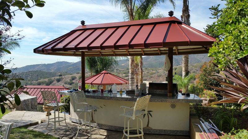 Red metal panel canopy over an outdoor BBQ bar